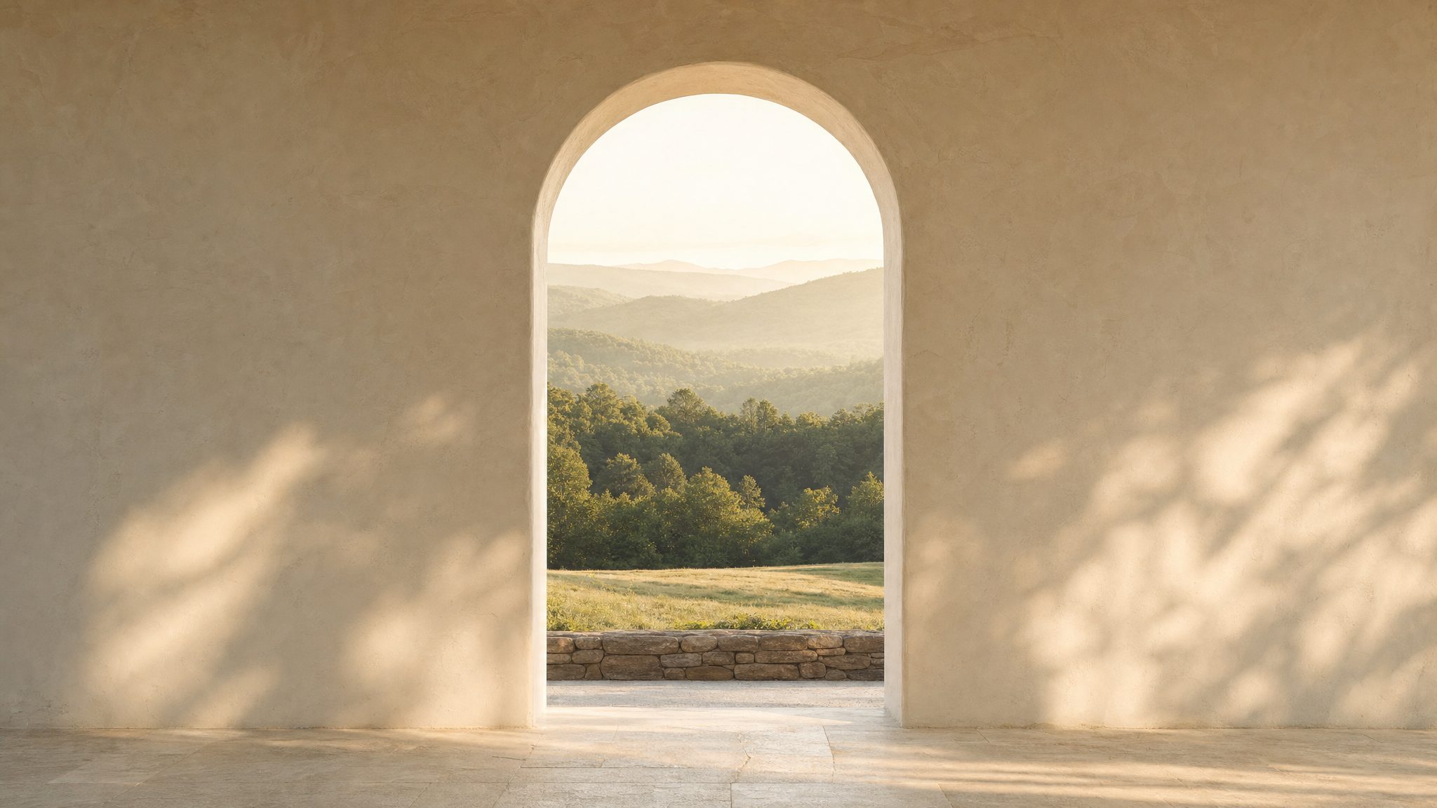 A sunlit arched room opening onto a calm green landscape